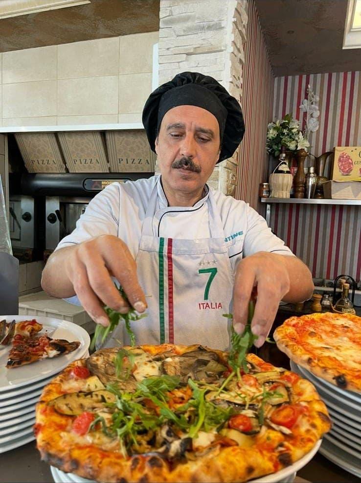 Le pizzaiolo finissant une pizza aux légumes grillés