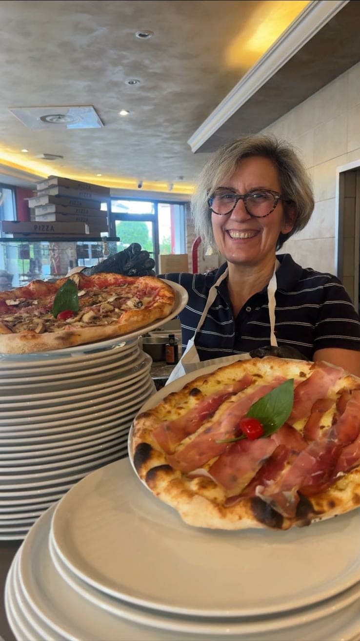 La patronne de Vice Versa présentant deux pizzas au comptoir