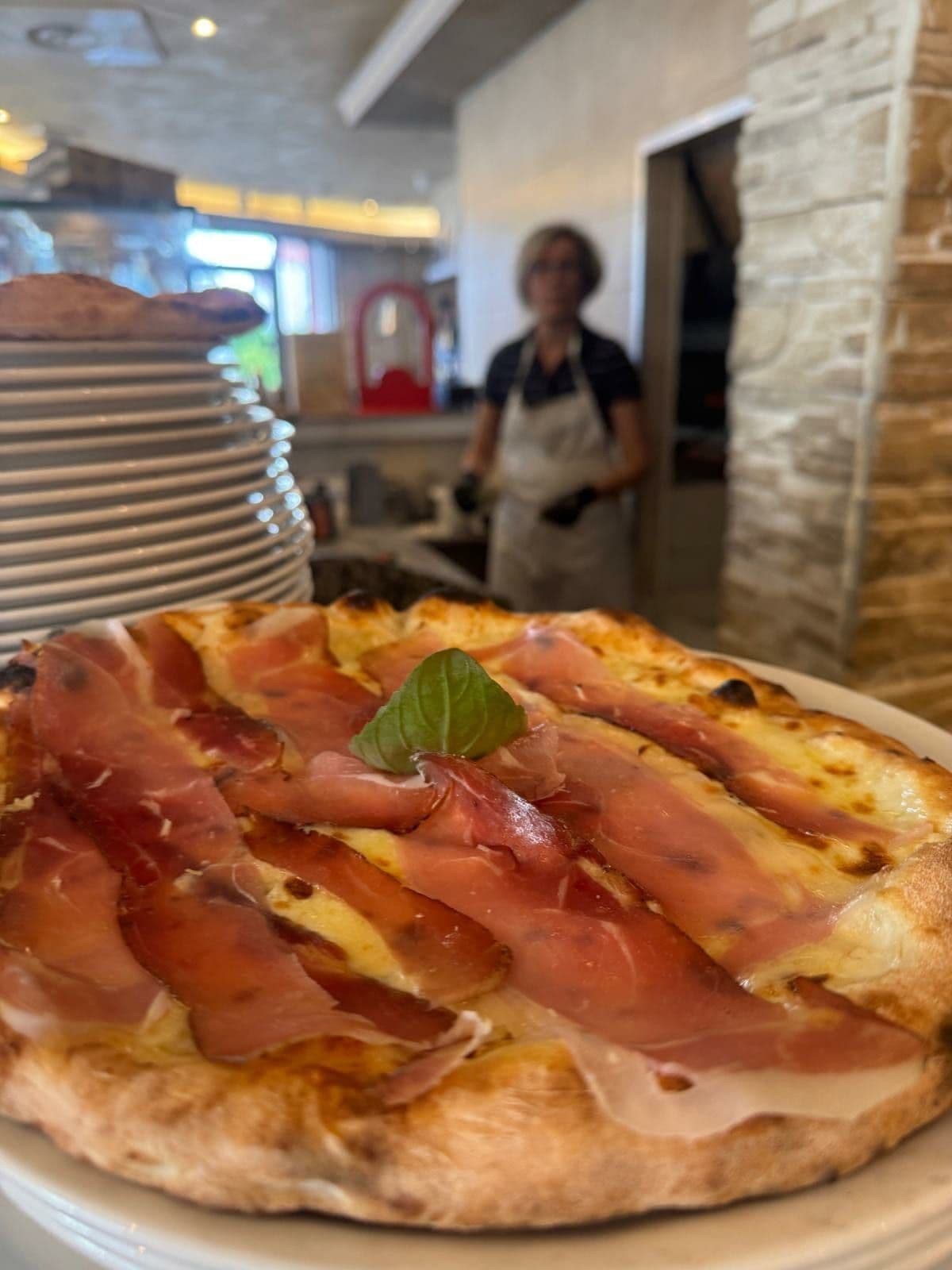 Pizza au jambon de Parme et basilic sortant du four